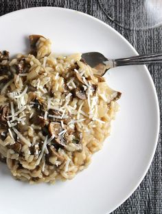 a white plate topped with pasta covered in mushrooms and grated parmesan cheese