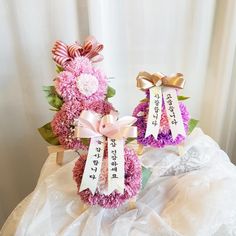 two pink and purple flowers with ribbons on them