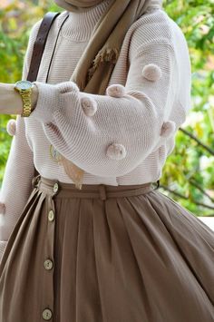 a woman wearing a white sweater and brown skirt with her hands on her hips while she is looking at the camera