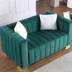 a living room with a green couch and white pillows on the end table in front of it