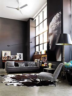 a living room filled with furniture and a large window covered in pictures on the wall