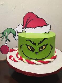 there is a green cake decorated with the grinch face and candy canes on top