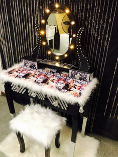 a vanity table with a mirror and lights on the top, in front of a curtained wall