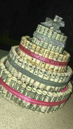 a cake made out of stacks of money on top of each other with pink ribbon