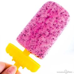 a hand holding a popsicle that is pink and yellow