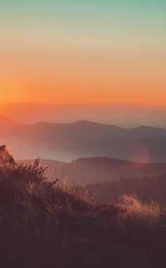 the sun is setting over some hills and trees