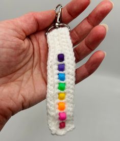 a hand holding a keychain made out of crochet with rainbows on it