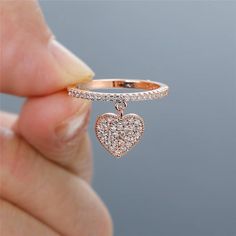 a close up of a person holding a ring with a heart on it