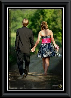 a man and woman walking down a dirt road holding hands