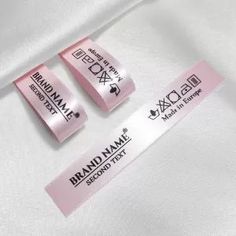 two brand name labels on a white shirt with pink ribbon around the neck and bottom