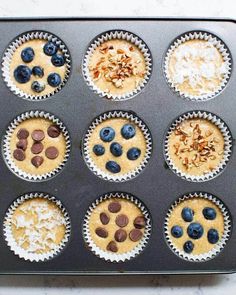 a muffin tin filled with cupcakes topped with blueberries and nuts