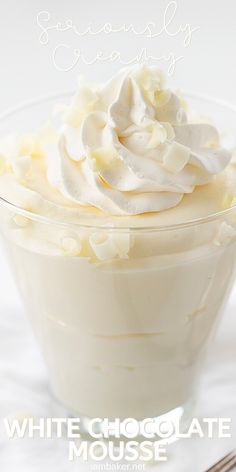 a white chocolate mousse with whipped cream in a glass bowl next to a fork