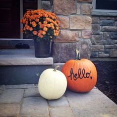 two pumpkins with the word hello written on them are sitting in front of a house