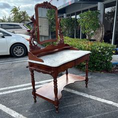 an old wooden vanity with a mirror on it's stand in a parking lot