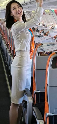 a woman in white dress standing on an airplane with her hand up to the sky