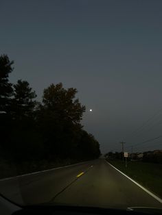 the moon is setting over an empty road