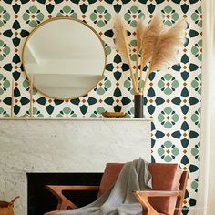 a living room with a fireplace, mirror and chair in front of a patterned wall