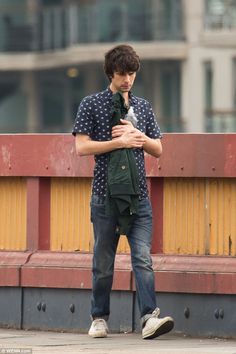 a young man standing on the street with his hands folded in front of his chest