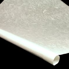 a roll of white paper sitting on top of a black surface