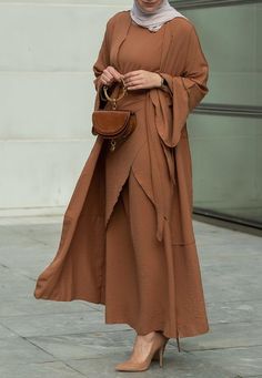 Introducing the Deluna three piece maxi lightweight abaya in rustic brown. This elegant and versatile design is perfect for any season and includes a long sleeve slip dress, apron piece, and a throw over abaya. The fabric is specially designed to resist wrinkles and the contrast brown color overlook seam at the edge of the abaya stands out.The abaya is super lightweight and flowy making it perfect for hot weather. The apron piece allows you to adjust the fit and the pattern of the abaya is not o Modest Maxi Length Abaya For Fall, Fall Season Modest Maxi Length Abaya, Fall Modest Maxi Length Abaya, Long Sleeve Brown Sets For Fall, Brown Long Sleeve Sets For Fall, Modest Long Abaya For Fall, Fall Solid Color Maxi Length Abaya, Modest Long Brown Maxi Dress, Elegant Long Sleeve Brown Abaya