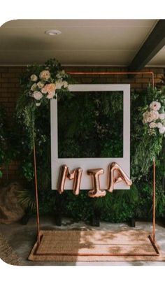 an outdoor wedding ceremony with greenery, flowers and the word mr and mrs spelled in copper letters