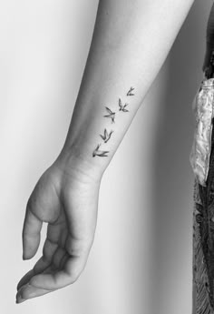 a woman's arm with an arrow tattoo on the left side of her wrist