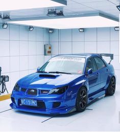 a blue car parked in a garage next to a camera set up on the wall