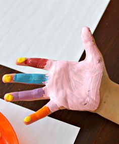 a child's hand painted with pink and orange