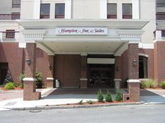 the front entrance to a hotel with trees and bushes