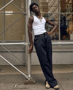 a man leaning against a metal pole on the sidewalk in front of a tall building