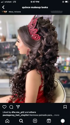 a woman in a red dress sitting down with long curly hair and a tiara on her head