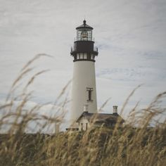 a tall light house sitting on top of a lush green field under a cloudy sky