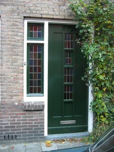 a green door and window in front of a brick building