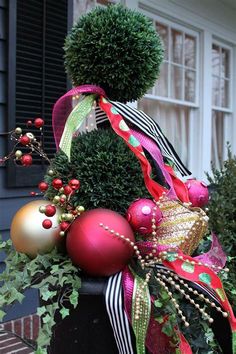 christmas decorations on top of a planter in front of a house