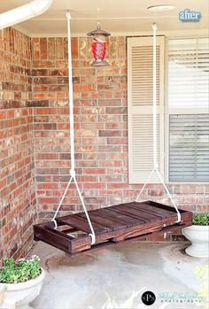 a porch swing that is attached to a brick building