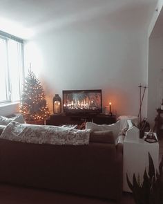 a living room filled with furniture and a christmas tree in front of a fire place