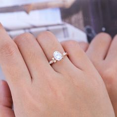 a woman's hand holding an engagement ring with two diamonds on it and the other hand