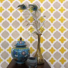 two vases and a bird on a table in front of a wallpapered background