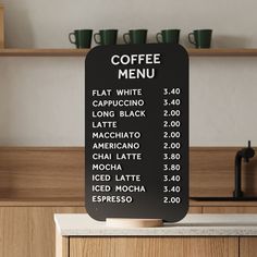 a black menu board with coffee cups on it in front of a wooden counter top