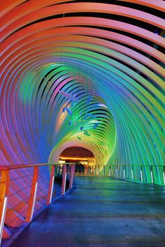 the inside of a tunnel with colorful lights on it's walls and walkways