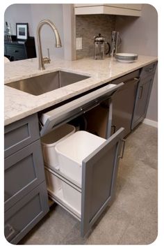 a kitchen sink with an open cabinet in the middle and a pull out dishwasher