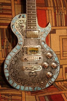 an intricately designed guitar sitting on top of a colorful wallpapered flooring