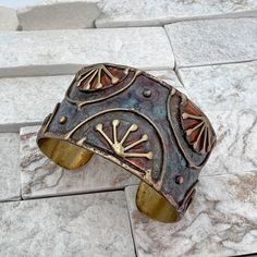 a metal cuff bracelet sitting on top of a stone floor