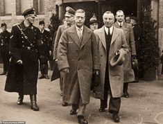 an old black and white photo of two men in suits walking down the street together