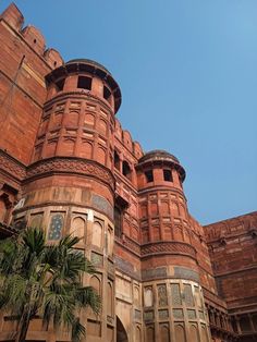 an old brick building with palm trees in the foreground and a blue sky behind it