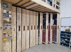 the inside of a storage room with wooden doors and shelves filled with tools, supplies and other items