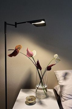 a lamp that is on top of a table next to a vase with flowers in it