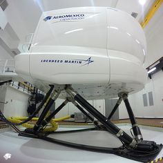 a large white boat sitting inside of a building with yellow hoses on the floor