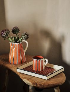 an orange and white striped mug sitting on top of a wooden table next to a book