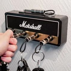 a person is holding keys to a marshall guitar amplifier wall mounted on a white wall